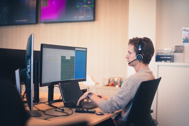 One of our employees sitting at his desk, looking at two monitors.